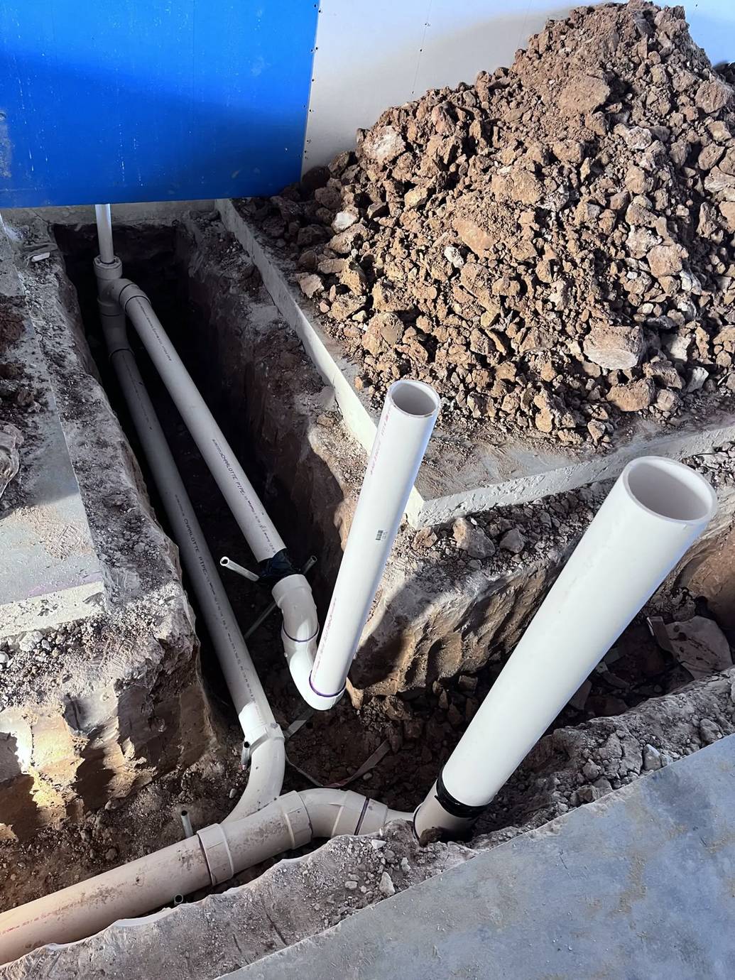 New PVC drain lines in a trench under a commercial slab