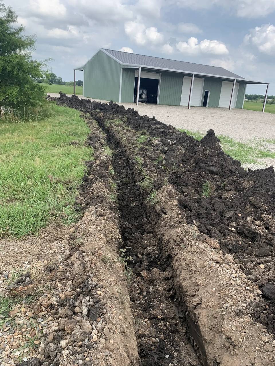 Sewer line trench running to a new metal shop building
