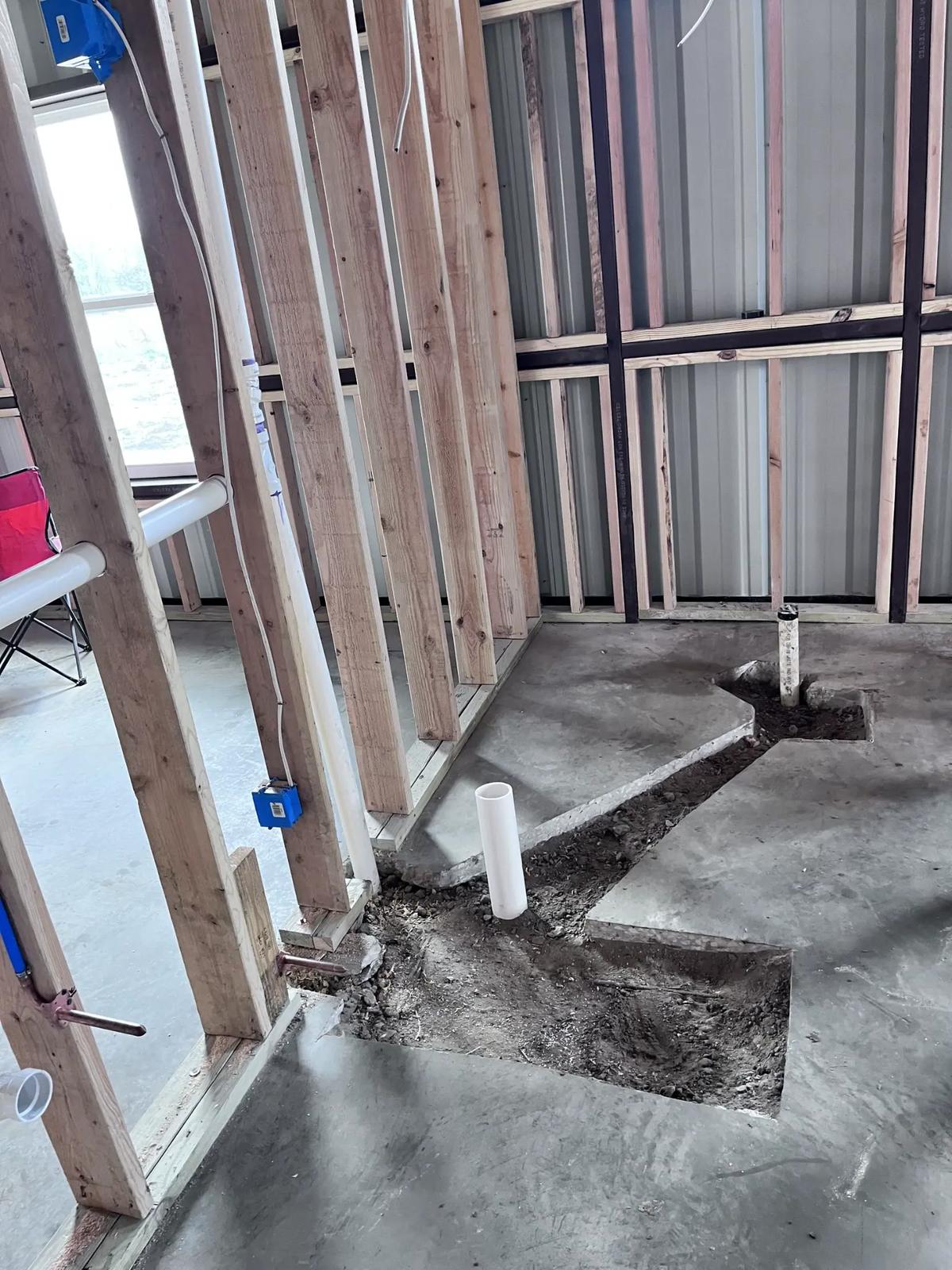 Slab cut open for new drain rough-in inside a metal building