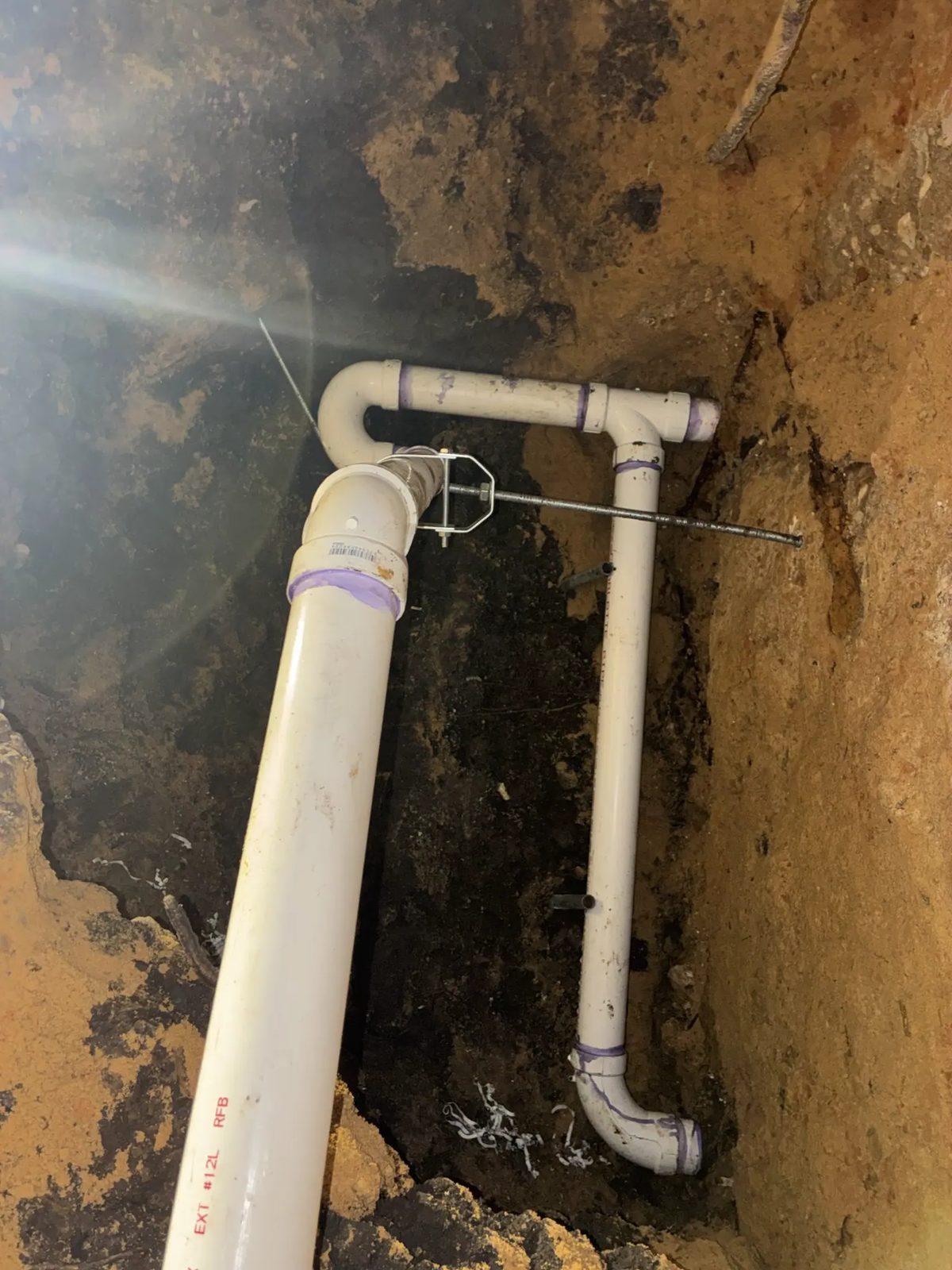New drain line supported with threaded rod and hangers inside a tunnel under a house